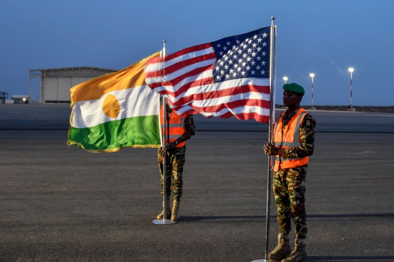 d8a8-1726565039 Two Nigerien soldiers hold the American and Nigerien flags on Air Base 101 in Niamey on June 7, 2024 during the ceremony for the first departure of American troops from Niger. (Photo by BOUREIMA HAMA / AFP)