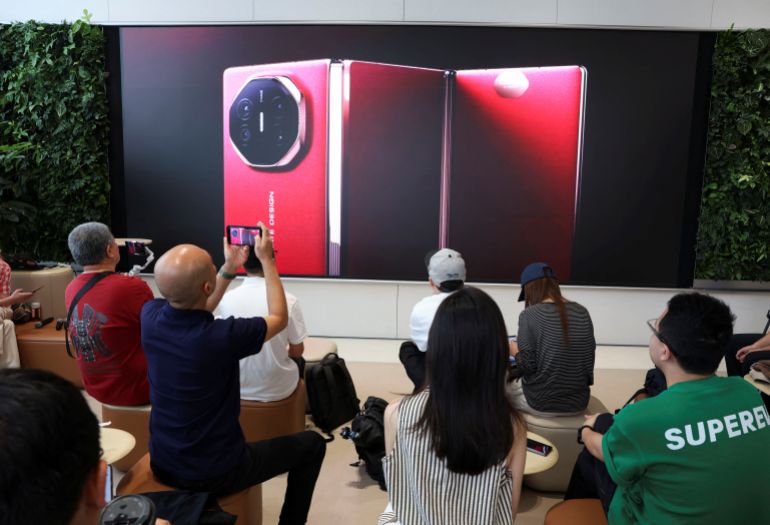 People watch the launch event of Huawei’s new Mate XT, a three-way foldable smartphone, live-streamed at a Huawei flagship store in Beijing, China September 10, 2024. REUTERS/Florence Lo