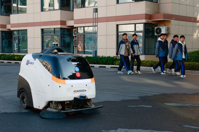 JINHUA, CHINA - JANUARY 14: AI sweeping robot automatically cleans the road in the campus of Zhejiang Traffic Technician College on January 14, 2026 in Jinhua, Zhejiang Province of China. AI sweeping robot operates along planned routes and autonomously avoids obstacles, empowering campus cleaning with technology. (Photo by Pan Qiuxia/VCG via Getty Images)
