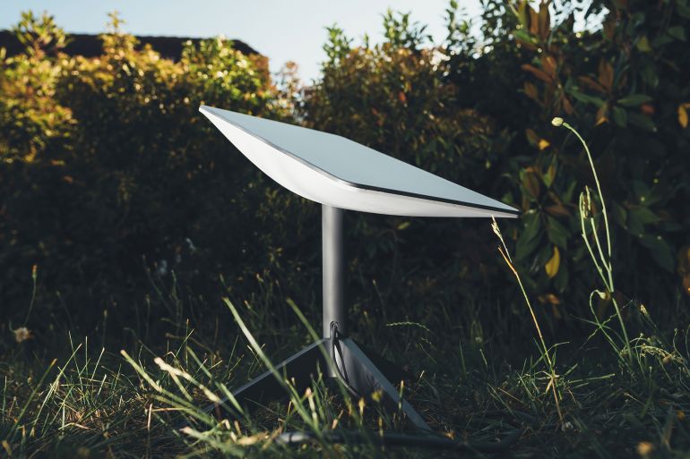 Germany - Jun 16, 2023: One Starlink antenna stands in a garden at sunset, searching for SpaceX satellites. Illustrative editorial for business and reliable internet connection where no mobile coverage or fixed line exists.