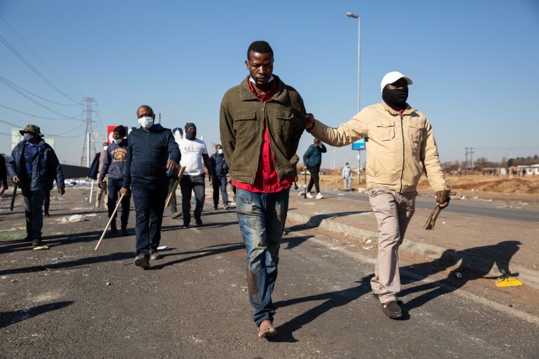 JOHANNESBURG, SOUTH AFRICA - 14 JULY: Vigilantes escort a man who they detained and accused of looting on July 14, 2021 in Vosloorus, Johannesburg, South Africa. South Africa has deployed the military to quell spasms of civil unrest and looting sparked by last week's imprisonment of former president Jacob Zuma, but also fueled by high unemployment and social and economic fallout from the Covid-19 pandemic, which has hit the country hard. (Photo by James Oatway/Getty Images)