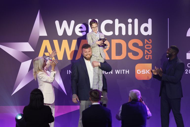 LONDON, ENGLAND - SEPTEMBER 8: Recipient of Inspirational Young Person 15-18 award, Declan Bitmead, is held up by Tom Stoltman, watched by Gladiator Phantom (Toby Olubi) and Gaby Roslin at the annual WellChild Awards 2025, which celebrates the achievements and resilience of seriously ill youngsters and their families, at the Royal Lancaster Hotel on September 8, 2025 in London, England. (Photo by Aaron Chown - Pool/Getty Images)