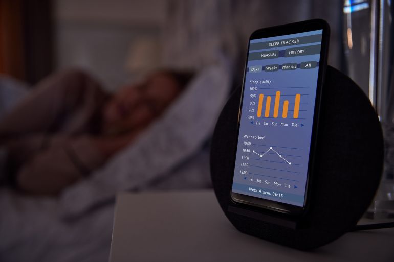 Woman Sleeping In Bed With Sleep Data App Running On Mobile Phone On Bedside