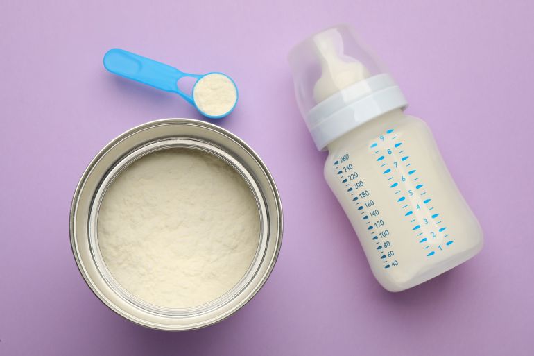 gettyimages-1403248652 Feeding bottle with infant formula and powder on violet background, flat lay GettyImages-1403248652
