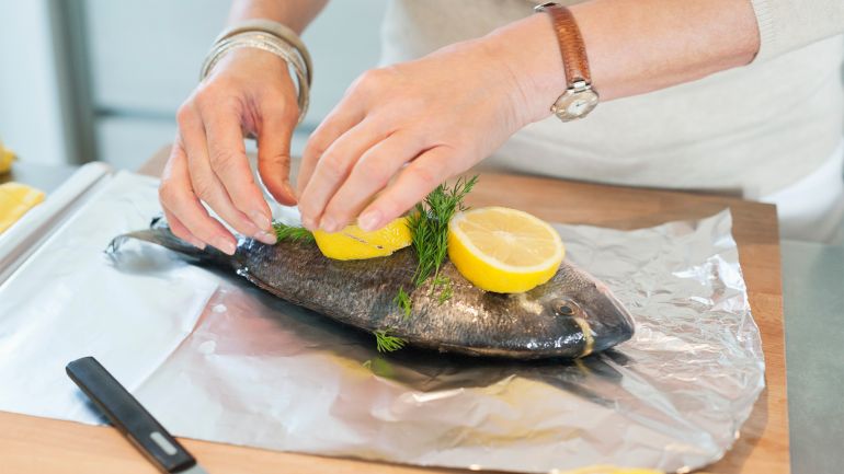 Elderly woman preparing seafood in a kitchen