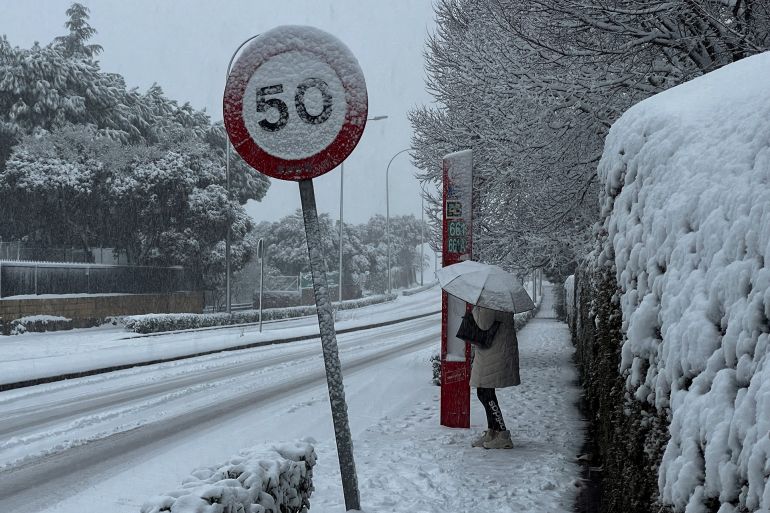portugal-3-1769620592 A woman holds an umbrella to protect herself while waiting for a bus as storm Kristin hits several parts of Spain and Portugal, in Galapagar, on the outskirts of Madrid, Spain, January 28, 2026. REUTERS/Silvio Castellanos