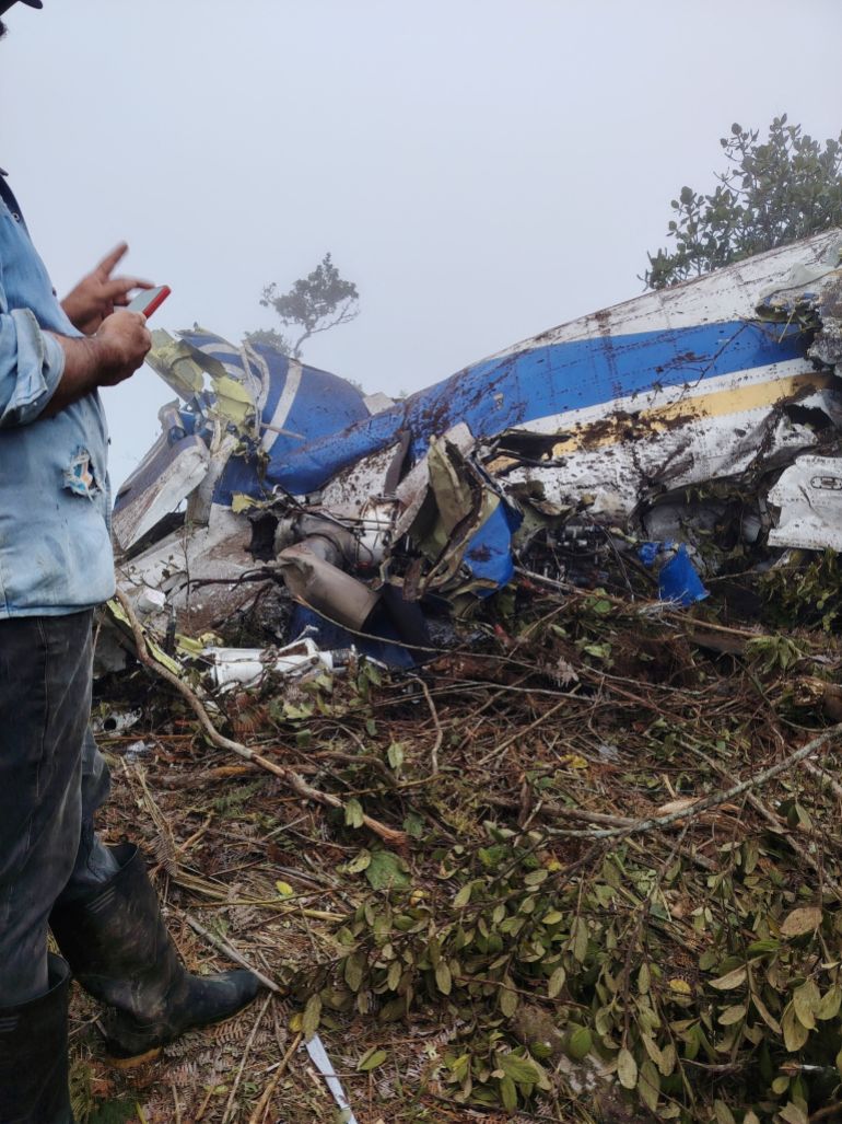 reuters_697b148b-1769673867 A person stands near the wreckage of a plane crash in Playa de Belen, North Santander, Colombia, January 28, 2026, in this picture obtained from social media. Notiplaya/via REUTERS THIS IMAGE HAS BEEN SUPPLIED BY A THIRD PARTY. MANDATORY CREDIT Verification lines:The location of the footage was confirmed from the source and authorities report of the plane crash. Reuters was also able to confirm the airline logo, colors and pattern of debris from wreckage that matched the SEARCA plane from file images. The date of footage was verified from original file metadata. FlightRadar24.com showed the flight taking off from Camilo Daza International Airport at around 16:40UTC and flew towards Ocana before disappearing on the radar at around 16:54UTC.