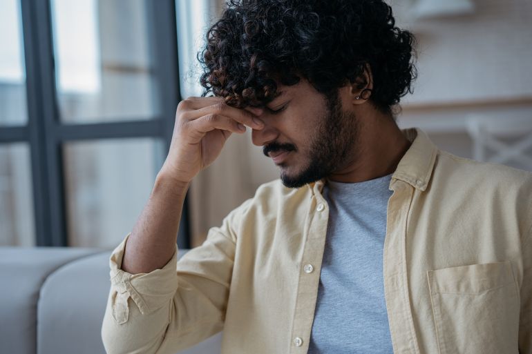 Close up portrait of tired stressed Indian man having headache feeling sick sitting at home. Man fired from work. Depression, pain, overwork concept ; Shutterstock ID 2126433518; purchase_order: aj; job: ; client: ; other: