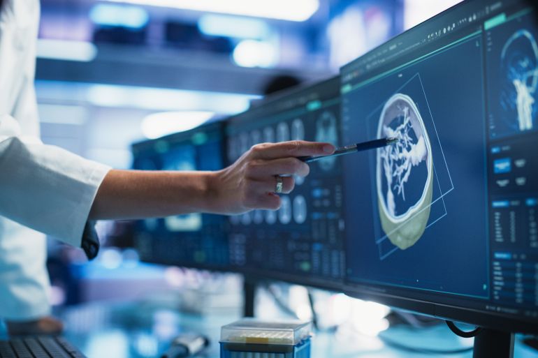 Modern Cancer Research Medical Center: Anonymous Doctor Pointing At Desktop Computer Monitor With 3D Software Visualizing Human Brain Based On CT Scan. Neurologist Looking For Tumor In Patient's Brain; Shutterstock ID 2456037017; purchase_order: aj; job: ; client: ; other: