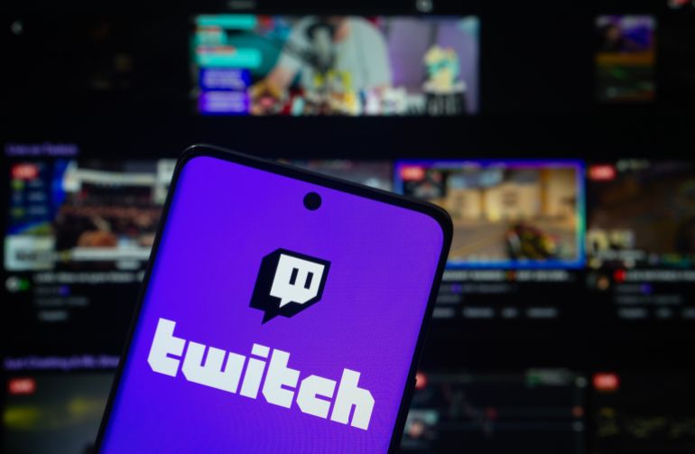 Dhaka, Bangladesh- 30 Sep 2025: Twitch logo is displayed on a smartphone screen, with the Twitch website visible on a computer screen in the background.