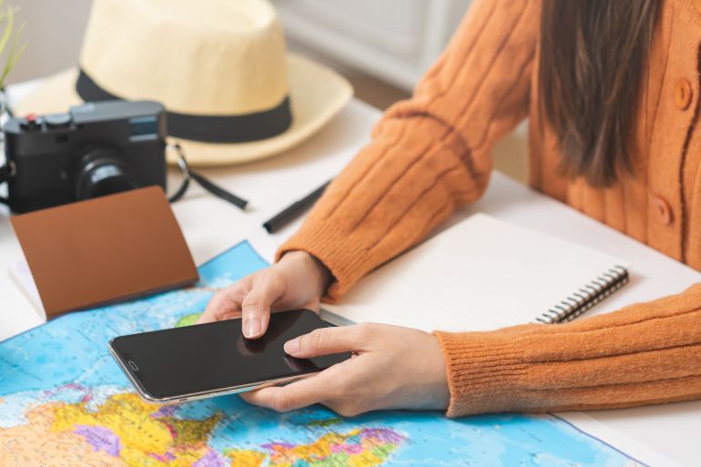 Travel planning, vacation, holiday trip, asian young tourist woman, girl hand using mobile phone, cellphone book flight ticket or check in online with passport, preparation for journey voyage trip.