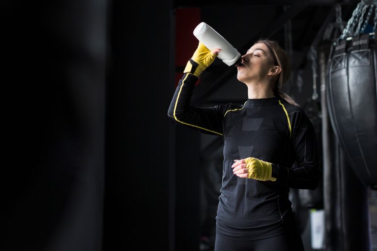 Side view of female boxer drinking water from flask freepik