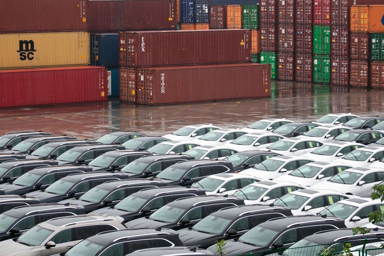32132132-1770465329 Jiujiang, China - May 14, 2022: Containers and neatly placed cars from ocean shipping companies around the world wait to be transported by shipping at Shanghai Port Group's Jiujiang Port Yard.