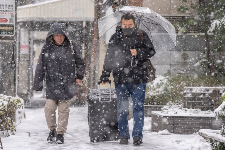 People walk through Nakano area during a snowfall in Tokyo on February 8, 2026. (Photo by Yuichi YAMAZAKI / AFP)