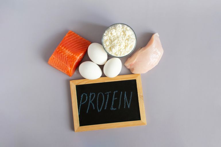 3protine-1760685649 Products containing a large amount of protein in their composition, close-up on a light background and the inscription on a dark sign "Protein"