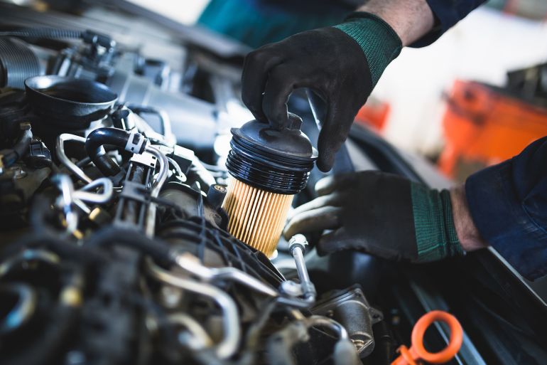 Close up hands of unrecognizable mechanic doing car service and maintenance. Oil and fuel filter changing. by Dusko ادوبي ستوك