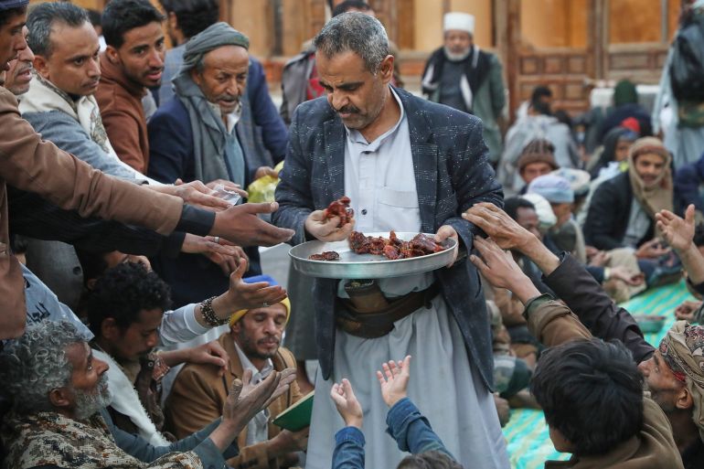 A volunteer distributes free food to break fast during the Muslim holy Islamic month of Ramadan at the Grand Mosque, in Sanaa, Yemen, Monday, Feb. 23, 2026. (AP Photo/Osamah Abdulrahman)