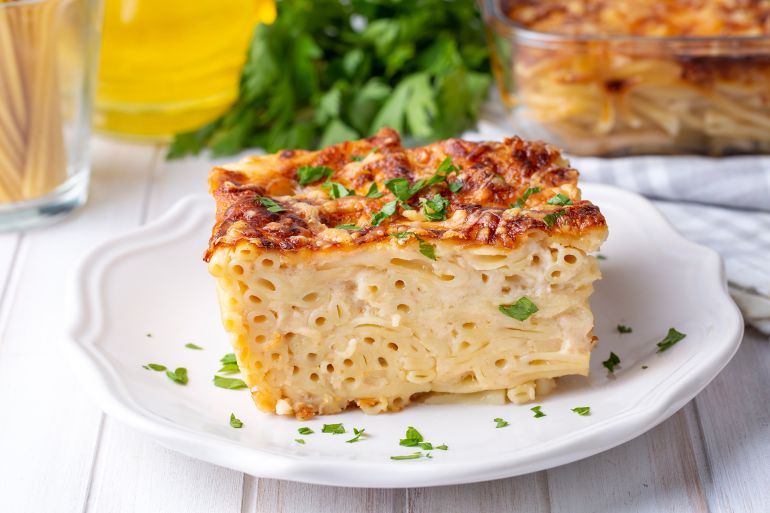 Pasta casserole bechamel sauce topped with melted mozzarella cheese and served in a white baking dish on a table (Turkish name; firinda makarna or firin makarna)