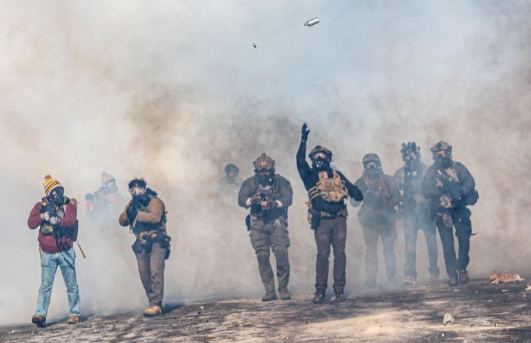 afp_6975317457a1-1769288052 A federal agent lobs a teargas canister towards protesters as agents advance through clouds of tear gas during clashes following the fatal shooting of a protester earlier in the day, on January 24, 2026 in Minneapolis, Minnesota.
