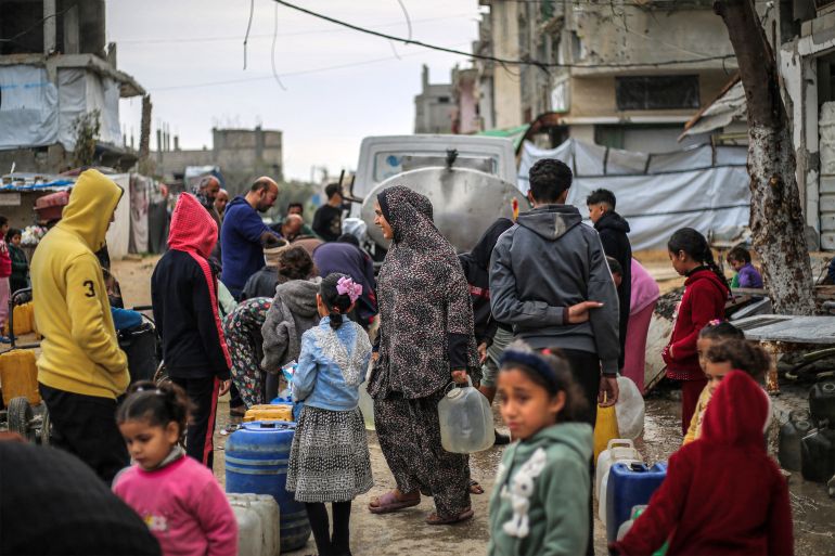 People queue to fill up containers with water from a portable cistern, in the Nuseirat camp for Palestinian refugees north of Deir al-Balah in the central Gaza Strip on January 29, 2026.