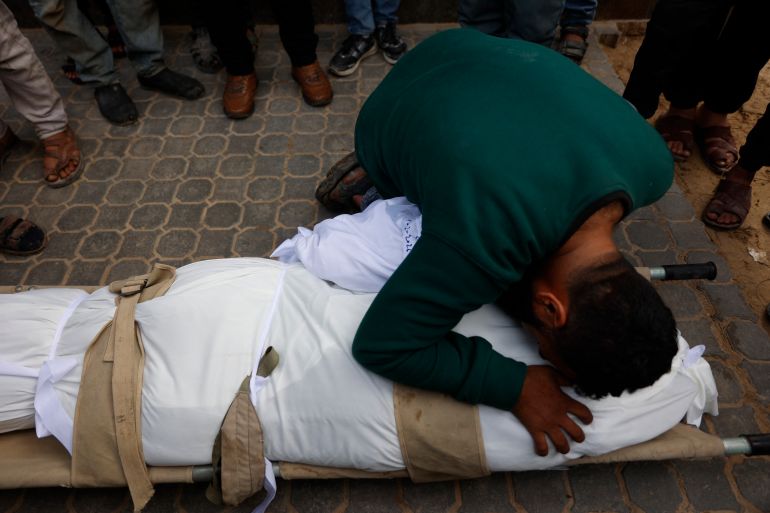 afp_69832f9443bb-1770205076 A man mourns over the body of a Palestinian victim who was reportedly killed in Israeli strikes earlier in the day, at Al-Shifa Hospital in Gaza City on February 4, 2026.