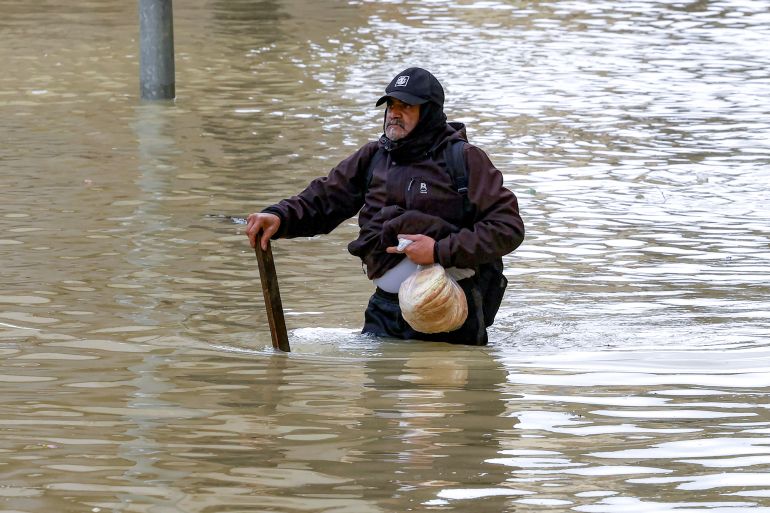 TOPSHOT - An elderly man walks through an inundated main street carrying a bag of loaves of pita bread in Morocco's northwestern city of Ksar el-Kebir on January 29, 2026, as several neighbourhoods flooded in the city due to a rise in the water level of the Loukkos river following recent heavy rainfall.