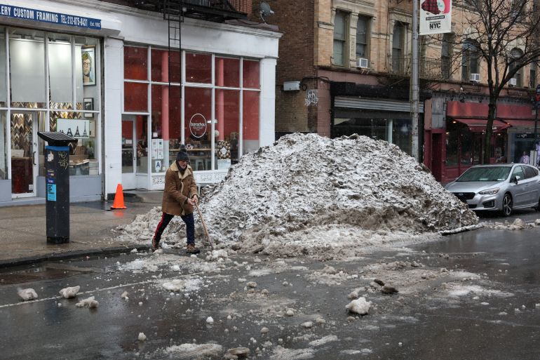 A man shovels a pile of snow from the recent snowatorm ahead of a new major winter storm in New York on February 22, 2026.