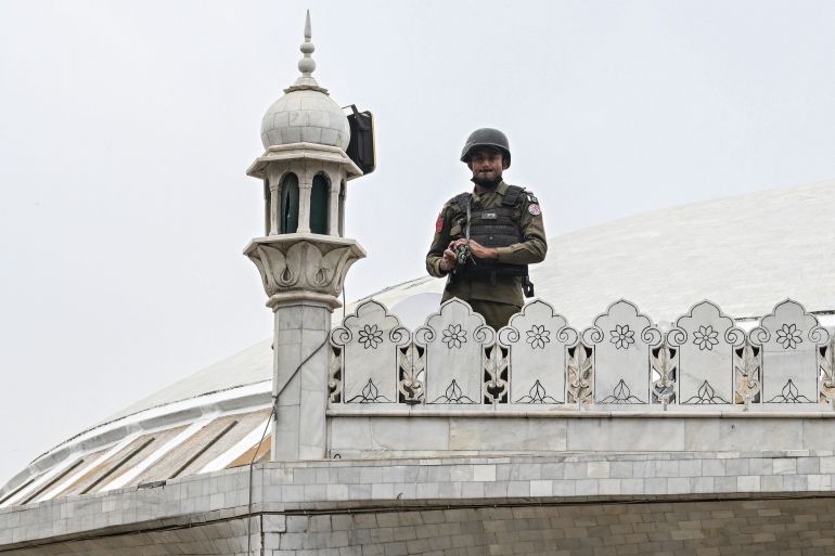 afp_69a1891fcd63-1772194079 A security personnel stand guard as Muslim devotees offer Friday prayers during the Islamic holy fasting month of Ramadan at a mosque in Lahore on February 27, 2026. (Photo by Arif ALI / AFP)