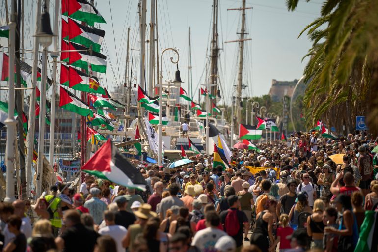 People crowd the dock ahead of the launch of a civilian flotilla bound for Gaza, aiming to break the Israeli blockade and deliver humanitarian aid in Barcelona, Spain, Sunday, Aug. 31, 2025. (AP Photo/Emilio Morenatti)