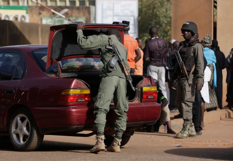 ap_6981d7329592e-1770116914 FILE - In this file photo taken Sunday, Jan. 17, 2016, Police officers search a car outside the gate of the hospital where victims of Saturday's attack at the Splendid Hotel are receiving treatment in Ouagadougou, Burkina Faso. The violence in Bamako and Ouagadougou underscores how danger has moved from the jihadist strongholds far in the desert to the very places where Westerners stay and eat while working in the region. (AP Photo/Sunday Alamba,File)