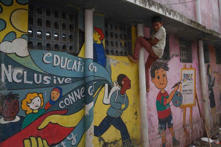 A boy climbs on a pipe next to a wall showing a mural by the Rouble Nagi Art Foundation in the Dhobi Ghat area of Mumbai, India, Thursday, Feb. 5, 2026.(AP Photo/Rafiq Maqbool)