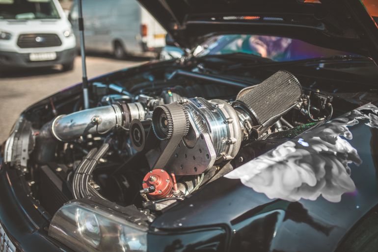 This image showcases the intricate details of a modified car engine, highlighting its powerful supercharger system