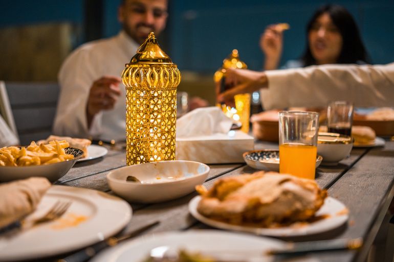 fghf6gf-1771318574 A group of young Arabic friends enjoys a cozy rooftop Ramadan dinner. Golden lantern light enhances the warm atmosphere with traditional dishes and drinks.