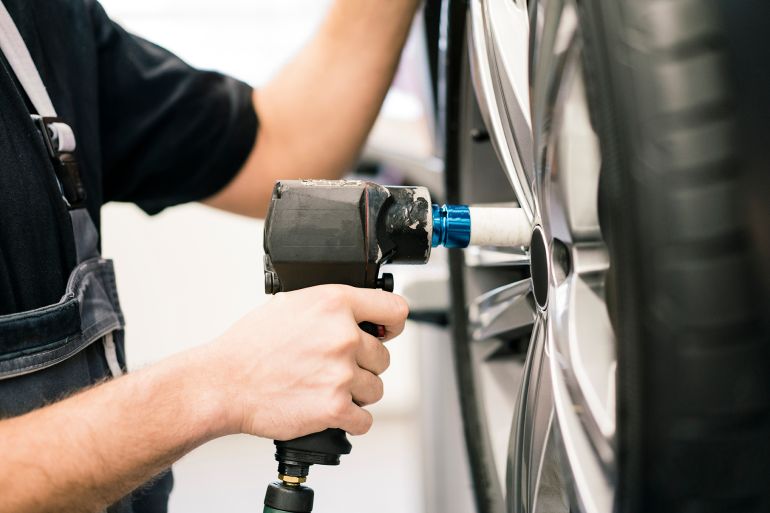 Close-up of car mechanic in a workshop changing tire