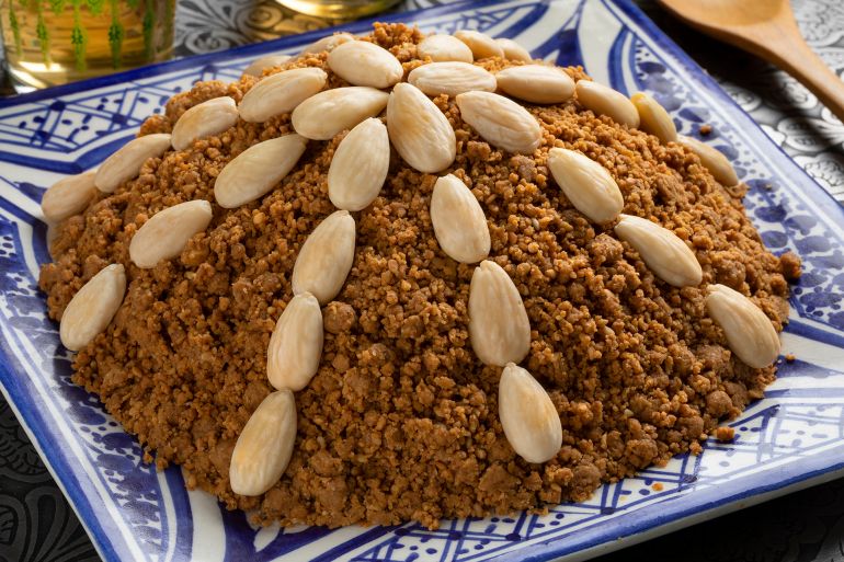 Dish with traditional Moroccan homemade sellou decorated with roasted almonds close up