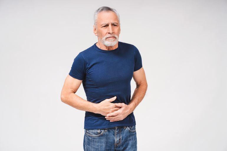 Portrait of sad senior gray-haired man touching his belly because of pain isolated over white background. Health care, medicine, lifestyle concept