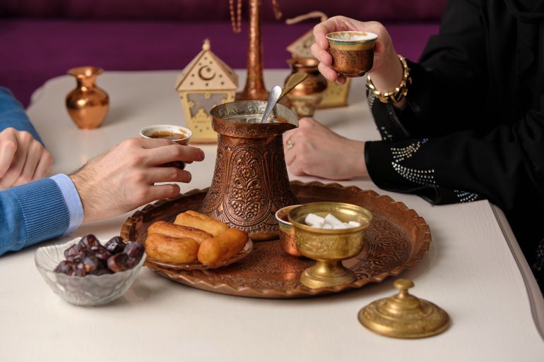 Happy Muslim family drinking traditional coffee with dessert at home celebrating eid al fitr. Eid Mubarak Ramadan Kareem.