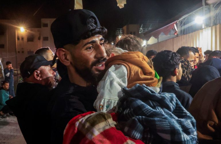 reuters_698b4ac8-1770736328 A man holds a child as Palestinians coming from the Rafah border crossing arrive at Nasser Hospital in Khan Younis in the southern Gaza Strip, February 9, 2026. REUTERS/Haseeb Alwazeer