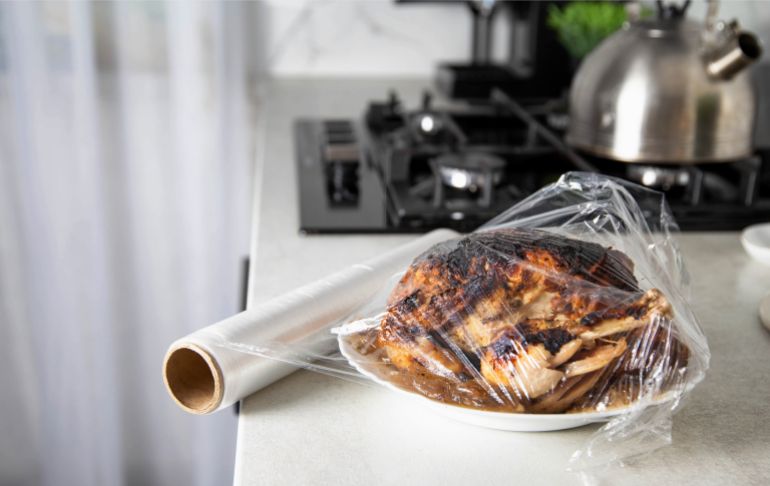 shutterstock_2206960879-1771082616 A plate with fried chicken wrapped in cling film in the kitchen, close-up. Storing food in the refrigerator.