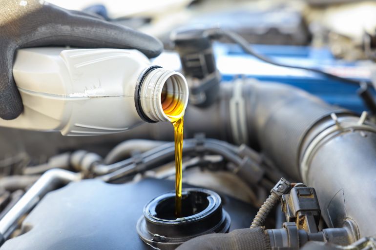 Man pouring motor oil into car engine, closeup; Shutterstock ID 2551385347; purchase_order: aj; job: ; client: ; other: