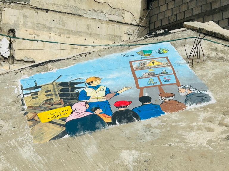 ‎⁨جدارية توعوية على أنقاض مبنى مدمر في غزة تحذر من الاقتراب من المباني الآيلة للسقوط (الجزيرة)⁩.jpg