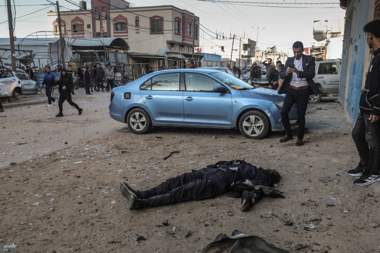 EDITORS NOTE: Graphic content / Men look on at body of a man that was killed in a Palestinian police jeep that was targeted by an Israeli air strike in Nuseirat refugee camp, in the central Gaza Strip on March 22, 2026. The killings by the Israeli military are the latest to rock the war-shattered Palestinian territory despite a ceasefire in place since October 10. The war on Gaza was sparked by Hamas's October 7, 2023 attack on Israel, which resulted in the deaths of 1,221 people. Israel's retaliatory assault on Gaza has killed at over 73,000 people, according to figures from the health ministry that the UN considers reliable. (Photo by EYAD BABA / AFP)