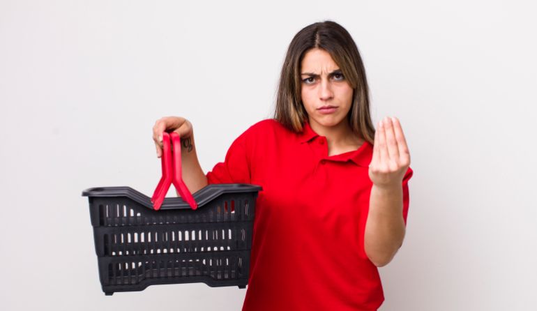 231-3-1773573612 pretty hispanic woman making capice or money gesture, telling you to pay. empty shopping basket concept فري بيك