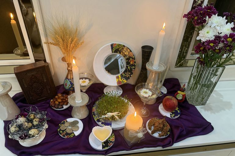 A candle burns on a Haft-Sin table, an arrangement of seven symbolic items which names start with the letter "S", to celebrate the spring holiday of Nowruz, in the home of an Iranian family in Tehran, on March 20, 2026.