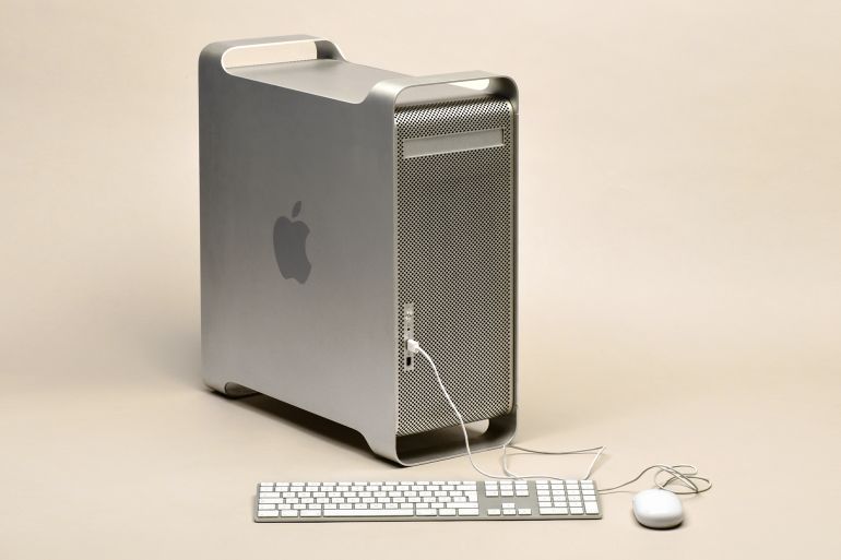 Milan, Lombardy, Italy - June 16, 2019: Apple Power Mac G5 computer in metal case with original Apple keyboard and mouse connected, isolated on beige background