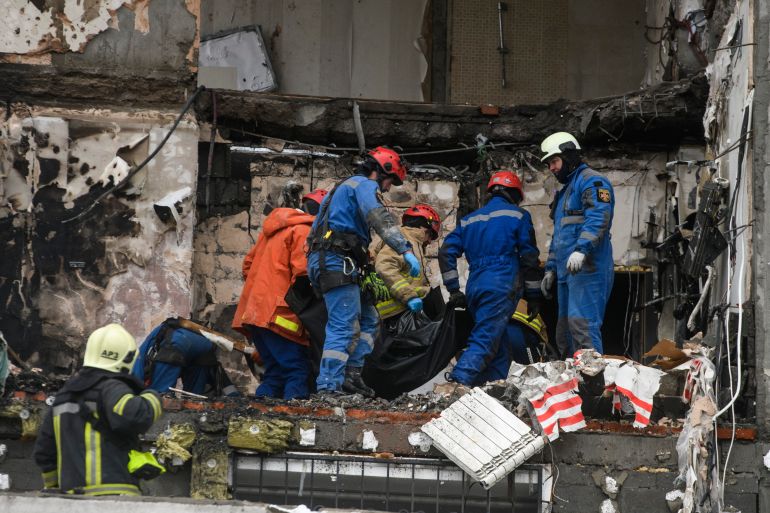 مسعفون أوكرانيون ينقلون جثة ضحية من مبنى سكني متضرر عقب هجوم روسي بمسيّرات وصواريخ على كييف، 27 ديسمبر/كانون الأول 2025، وسط الهجوم الروسي على أوكرانيا.