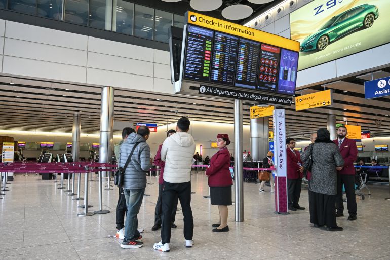 Staff from Qatar Airways help assist people with questions at their empty check-in area at London Heathrow Airport in west London on March 1, 2026, as flights are severely disrupted following the US and Israel's strikes on Iran.