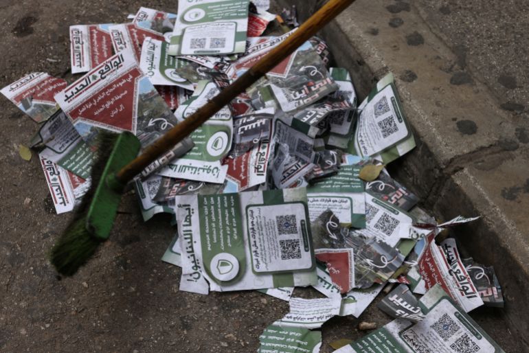 afp_69b41a4e9608-1773410894 TOPSHOT - A man sweeps warning leaflet dropped by the Israeli military over the Lebanese capital Beirut on March 13, 2026.