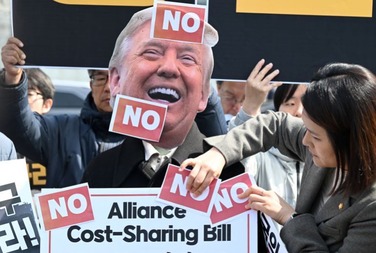 A South Korean protester wears a mask of US President Donald Trump during a protest against Trump's request to dispatch warships to the Strait of Hormuz in front of the US embassy in Seoul on March 16, 2026.