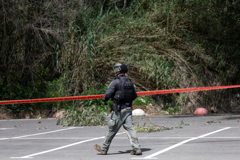 afp_69c7fd24104f-1774714148 A member of the Israeli security forces looks for the remains of a rocket fired from Lebanon by Hezbollah that reportedly targeted the northern Israeli border town of Kiryat Shmona on March 24, 2026.